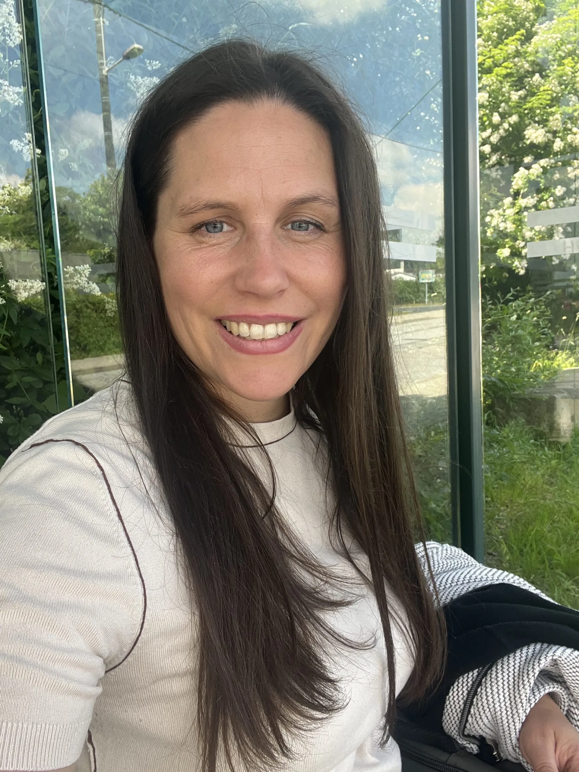 Woman with long brown hair and blue eyes smiling at the camera.